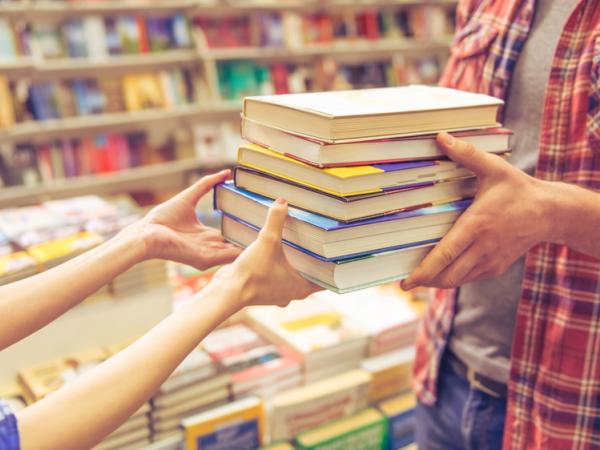 Woman handing books to customer at independent bookstore