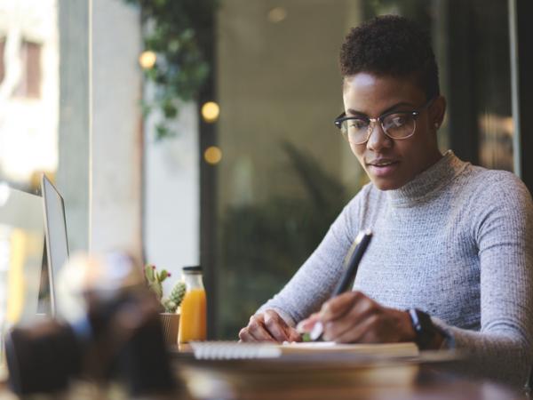 black woman writing in a cafe