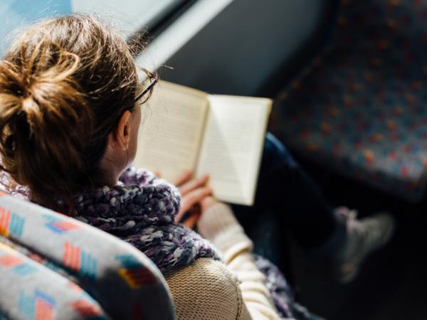 woman reading book on a bus 