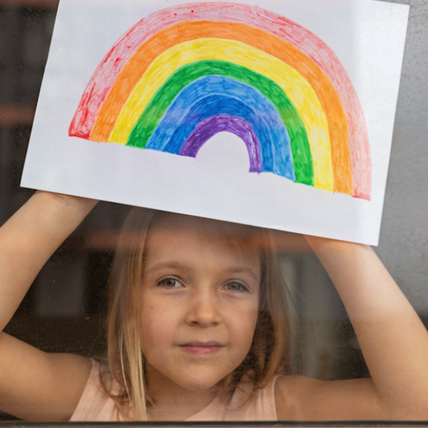 little girl showing rainbow drawing through the window