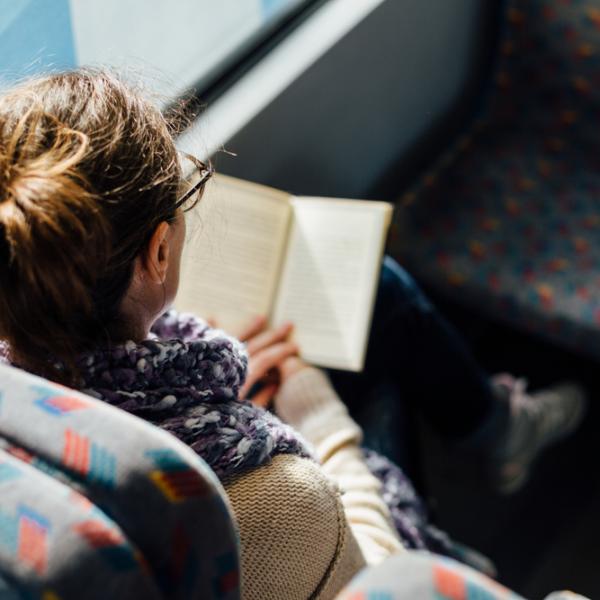 woman reading book on a bus 
