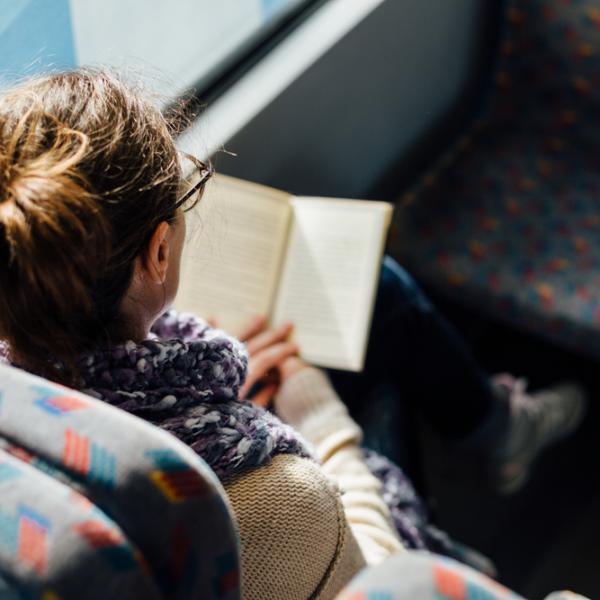 woman reading book on a bus