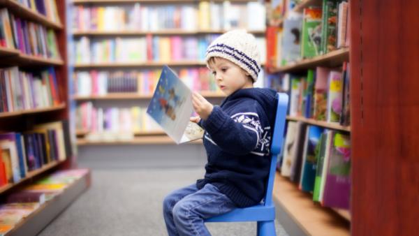 Child reading book in library