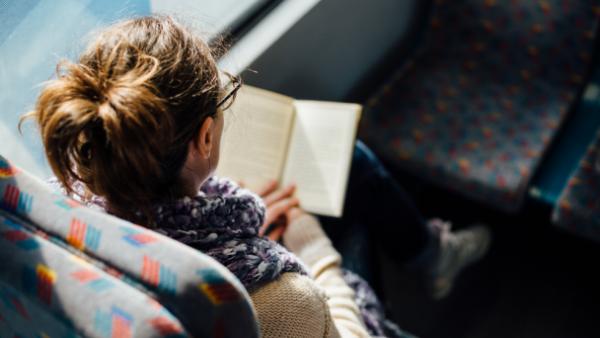 woman reading book on a bus 