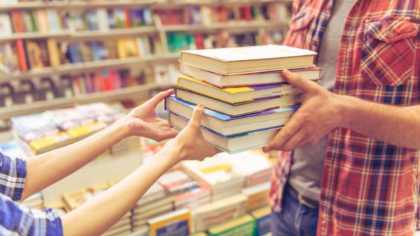 Woman handing books to customer at independent bookstore
