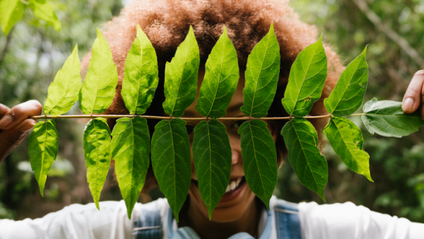 woman holding leave with her hands and hiding behind