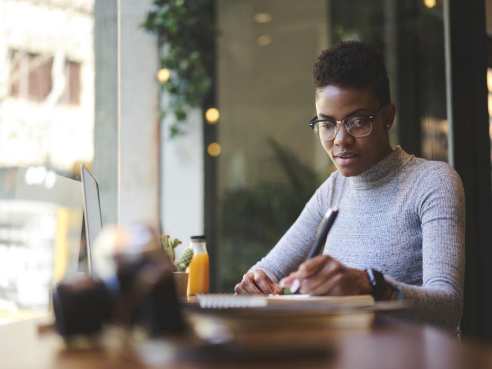 black woman writing in a cafe